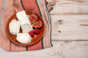 French organic matured white goat cheese with white rind close up served with fresh raspberries and figs