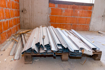 Heap of aluminum profiles for partition walls stacked on pallet, ready for mounting