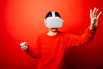 Studio portrait of a pre-adolescent boy with virtual reality glasses over a red background