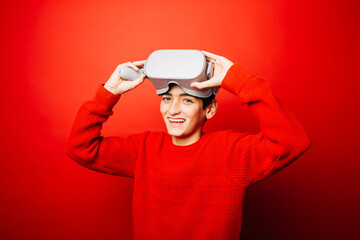 Studio portrait of a pre-adolescent boy with virtual reality glasses over a red background