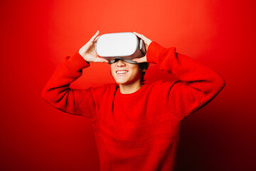 Studio portrait of a pre-adolescent boy with virtual reality glasses over a red background