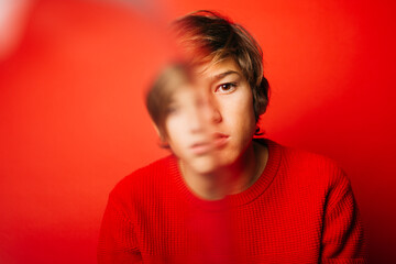 Fototapeta na wymiar Studio portrait of a thoughtful, blury pre-adolescent boy over a red background