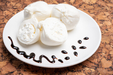 Eating of fresh handmade soft Italian cheese from Puglia, white balls of burrata or burratina cheese made from mozzarella and cream filling served with balsamico cream