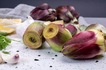 Heads of raw fresh purple romanesco artichoke vegetable and pilled hearts