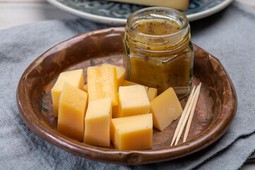 Cheese tasting, small pieces of old Dutch hard cheese and bowl with homemade dill-mustard sauce