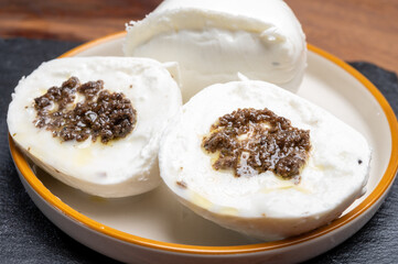 White balls of Italian soft cheese Mozzarella di Bufala Campana stuffed with black truffles mushrooms