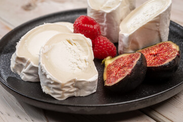 French organic matured white goat cheese with white rind close up served with fresh raspberries and figs