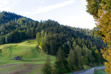 Fototapeta na wymiar Scenic landscape with green hills and meadows at mountain village Versam, Canton Graubünden, on a blue cloudy autumn day. Photo taken September 26th, 2022, Versam, Safiental, Switzerland.