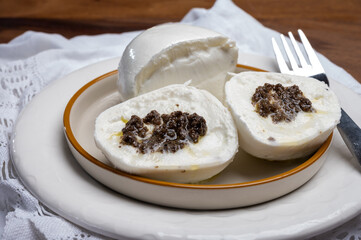 White balls of Italian soft cheese Mozzarella di Bufala Campana stuffed with black truffles mushrooms
