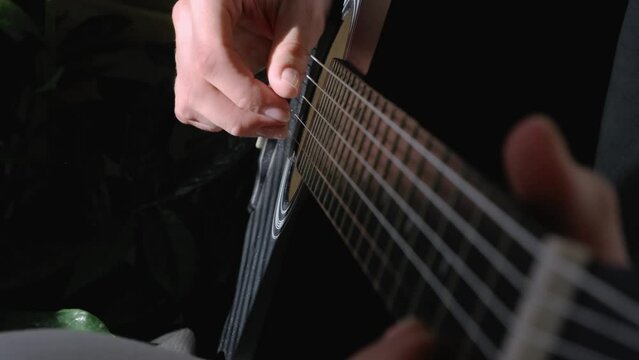unrecognizable woman singing song and playing acoustic guitar in sunny cottage bedroom, hobby relaxing, girl pinches chords with her fingers