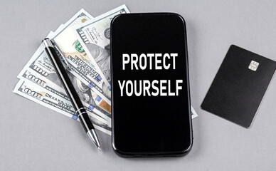 Credit card and text PROTECT YOURSELF on smartphone with dollars and pen. Business concept