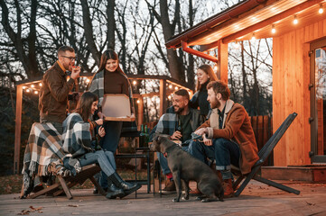 Cute dog. Group of people is spending time together on the backyard at evening time