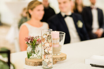 Beautiful table decorations in front of the bride and groom. Table decoration for a wedding on the North Sea beach. Intimate wedding on the beach. Shells as decoration