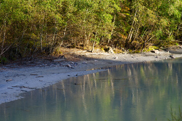 Reflections of trees in Rhine River at gorge of Anterior Rhine Valley on a sunny autumn day. Photo taken September 26th, 2022, Versam, Switzerland.