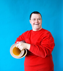 An adult man with a mental disorder syndrome holds a sports mat in his hands.