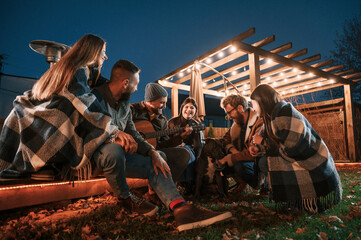 Having fun with dog. Group of people is spending time together on the backyard at evening time