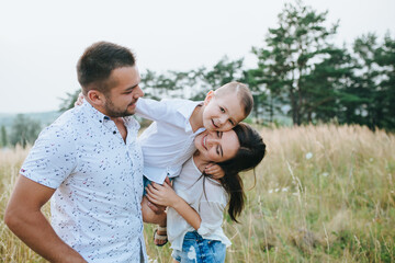 Happy young family father, mother and little son having fun outdoors, playing together in park