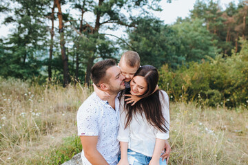 Happy young family father, mother and little son having fun outdoors, playing together in park