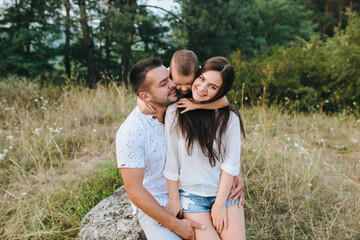 Happy young family father, mother and little son having fun outdoors, playing together in park