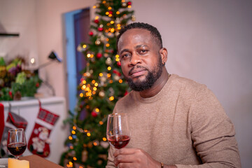 African American man with a glass of red wine celebrating Christmas and new year at home.