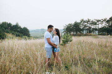 Happy in love romantic young cheerful couple man and woman walk together among the summer forest