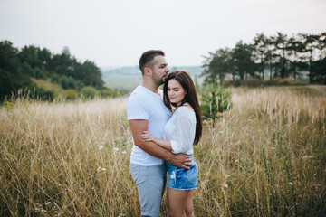 Happy in love romantic young cheerful couple man and woman walk together among the summer forest