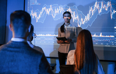 Exchange company. Female leader talking to employees, showing the plan on the projector in office...