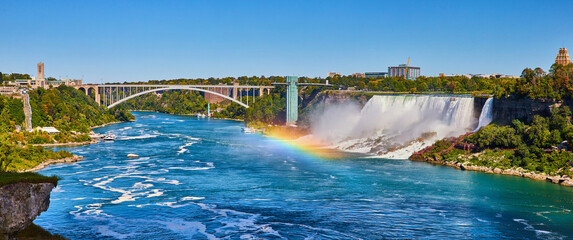 Fototapeta premium Stunning rainbow over Niagara River looking at American Falls and Rainbow Bridge