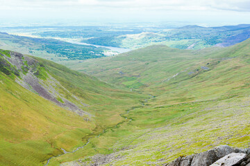 Climbing up mountain range in North Wales, United Kingdom. Rural landsapes, green grass, cloudy sky, selective focus