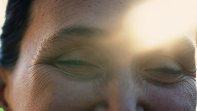 Macro close up of a happy 40 year old woman with lens flare sunlight