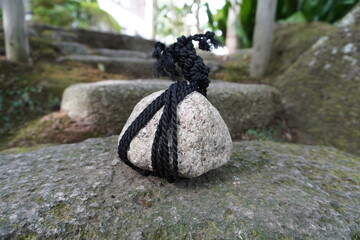 [Japan] A round stone tied up with a black rope, called 