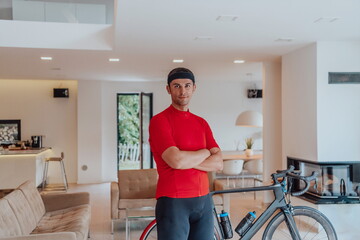Fototapeta na wymiar Photo of a determined triathlete standing in a modern large living room, behind him is his training bike
