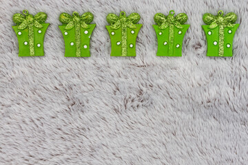 Green Christmas presents on gray plush material holiday background