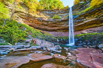 Fall foliage and layered cliffs by huge waterfall crashing towards lower river