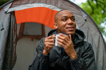 Man holding metal mug outside of tent © Cultura Creative