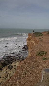 Chico mirando por un acantilado al mar en la costa gaditana 
