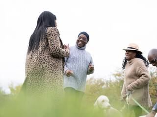 Senior couples standing with dogs and laughing in nature