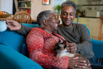 Senior couple with cat sitting on sofa