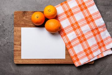 white paper with oranges checkered cloth on wood on dark marble background