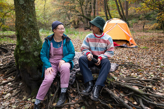 Smiling Female Friends Camping In Forest