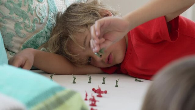 One small boy playing with toy soldiers. Child plays at home with tiny combat figurines
