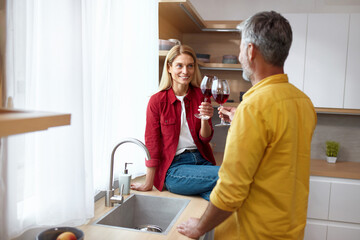Fototapeta premium Happy Couple Drinking Wine. Smiling Senior Spouses Holding Wineglasses With Tasty Red Wine. They Are Smiling And Drinking Their Drinks. Date And Love Concept 