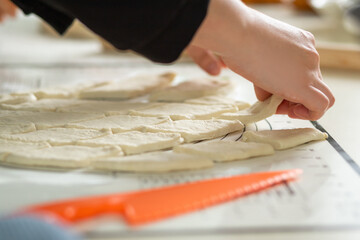 A close-up view of the hands of a housewife in the process of cooking baursaks in the kitchen.