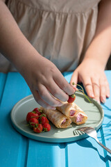 pancakes with cottage cheese and strawberries, healthy breakfast. female hands serve a plate of pancakes with fresh strawberries