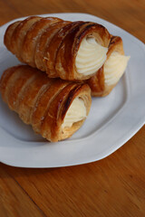 Italian traditional Cannoli filled with vanilla Custard cream on plate on wooden table