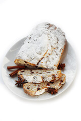 Traditional german sweet bread with raisins and candied fruits called Stollen on a plate isolated on white background