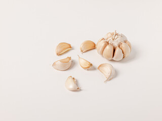 Large head of garlic and small cloves arranged on white background Put yourself aside to have copy space.