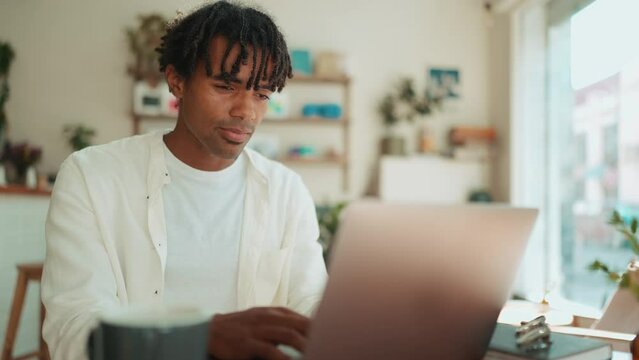 Confident African man working on laptop and talking in the cafe