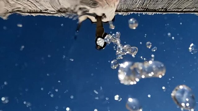 Unusual point of view of drinking fountain with water flowing downward on camera. Low angle slow motion