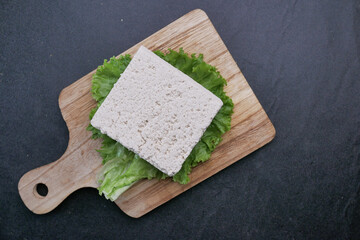 Top view of of tofu on a chopping board on black background 